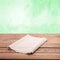 Empty tablecloth on wooden table with spring green background. Napkin close up top view mock up. Sophisticated Kitchen Aesthetic