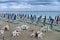 Empty tables and chairs, folded loungers and parasols, deserted, stormy sea