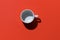 Empty tea cup on red paper background. Coffee mug from above. Minimal concept Hard deep shadow. Flat lay, top view