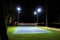 An empty tennis court at night, lit by bright lights