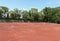 Empty tennis court on sunny summer day. View from above of red clay tennis court. Outdoor sports playground. Copy space