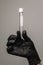 Empty test tube in a glass flask in the hands of a scientist or cosmetologist. Black gloves on a gray background. Experiment,