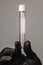 Empty test tube in a glass flask in the hands of a scientist or cosmetologist. Black gloves on a gray background. Experiment,