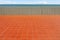 Empty tiled brown terracotta terrace. Gray concrete fence, sea and sky on background