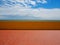 Empty tiled terracotta terrace with a yellow concrete fence at the end, in front to the sea and cloudy sky