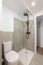 An empty tiny bathroom with a toilet and a glazed shower with gray tiles. The concept of a simple and stylish bathroom