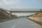 An empty toll road with a pedestrian bridge construction for the public crossing it