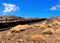 Empty two lane blacktop road in the desert with scrub plants arid landscape and blue sky with clouds