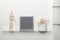 Empty vintage frame felt letter board, wooden manikin and basket with dried flowers on glass shelf against light wall and