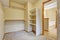 Empty walk-in closet with wood shelves, beige carpet floor.