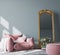 Empty wall mockup in modern living room with pink armchair and classic golden mirror on pastel interior background