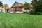 Empty well-groomed lawn with green grass is in front of modern cottage, backyard