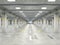 Empty well-illuminated large underground parking with concrete floor and columns