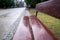 Empty wet brown bench, empty pathway in the park in Warsaw, Poland, blurred background