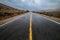 Empty wet desert asphalt pavement road with yellow highway marking lines