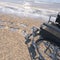 Empty wheelchair on a beach of sand with footprints