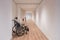 An empty wheelchair stands in an empty corridor of a care home with white walls