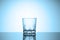 Empty whiskey glass stands on a glossy table with reflection. Cold blue tinted vignette