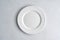 Empty white ceramic plate on light background. Copy space, top view, horizontal, closeup