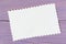 Empty white figured paper card on a light-violet wooden background