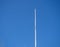 Empty white flagpole against the blue sky. Lowered flag