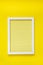 Empty  white frame on yellow texture hanging on  bright yellow wall