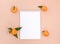 An empty white notebook and tangerines on a peach background. Template with space for text.