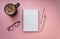 Empty white notebook top view on pink background close to pens, coffee and glasses