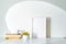 Empty white picture frame mockup in sunlight. Books, coffee cup and sphere-shaped vase with small yellow flowers. Concept of