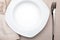 Empty white plate. On delicate beige tablecloth.