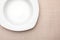 Empty white plate. On delicate beige tablecloth.