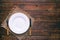 Empty white plate with fork and knife on rustic wooden background