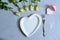 Empty white plate with hearts on Ultimate Gray background with white roses and fork. The moment of a wedding, anniversary,