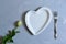 Empty white plate with hearts on Ultimate Gray background with white roses and fork. The moment of a wedding, anniversary,