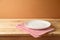 Empty white plate on wooden table with tablecloth.  Kitchen mock up for design and product display