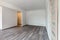 Empty white room with washed floating gray wooden laminate flooring and newly painted wall in background