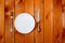 Empty white round plate with antique knife and fork on wooden background. Top View with text space.