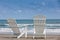 Empty white wooden chairs at a paradisiac beach on the tropics in a beautiful sunny day