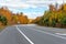 Empty winding highway through a forest on a partly cloudy autumn day