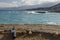 Empty wine bottle on the shore with the village Limeas Chersonisou in background