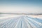 Empty winter road covered with snow on field in motion