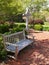 An empty wood bench by a cross and red brick patio