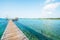 Empty wood bridge extending into the clear blue sea, bright summer morning, beautiful clouds and light blue sky