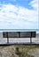 Empty wooden bench facing the sea along a boardwalk.