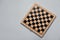 Empty wooden checkerboard on light grey background, top view. Space for text