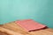 Empty wooden corner table with red checked tablecloth over mint wall background for product montage