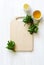 Empty wooden cutting board, fresh greens, olive oil and lemon juice