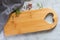 Empty wooden cutting board with heart, kitchen cloth and spices on light stone table