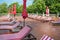 Empty wooden deck chairs with red and white striped mattresses stand in a row. Luxury outdoor recreation, sunshine