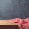 Empty wooden deck table with checked tablecloth over blackboard background